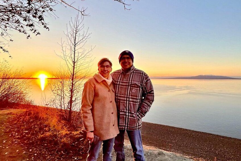 Two people standing on a beach with a sunset in the background. 5