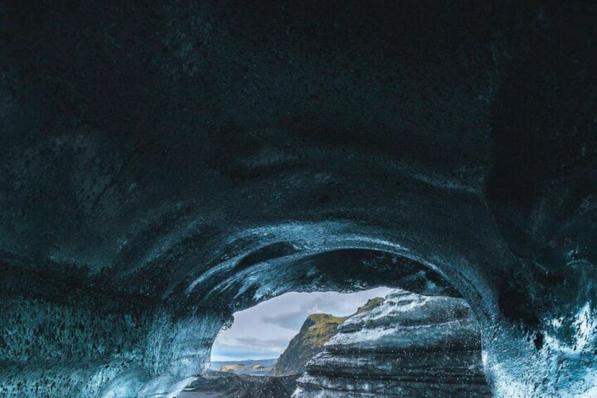 An ice cave with a view of a rocky landscape outside. 4