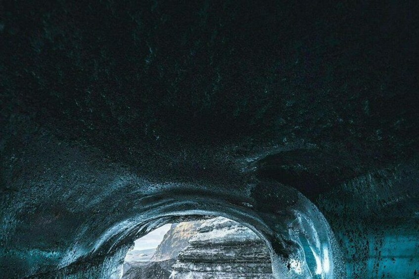 An ice cave with a tunnel leading to a bright opening. 4