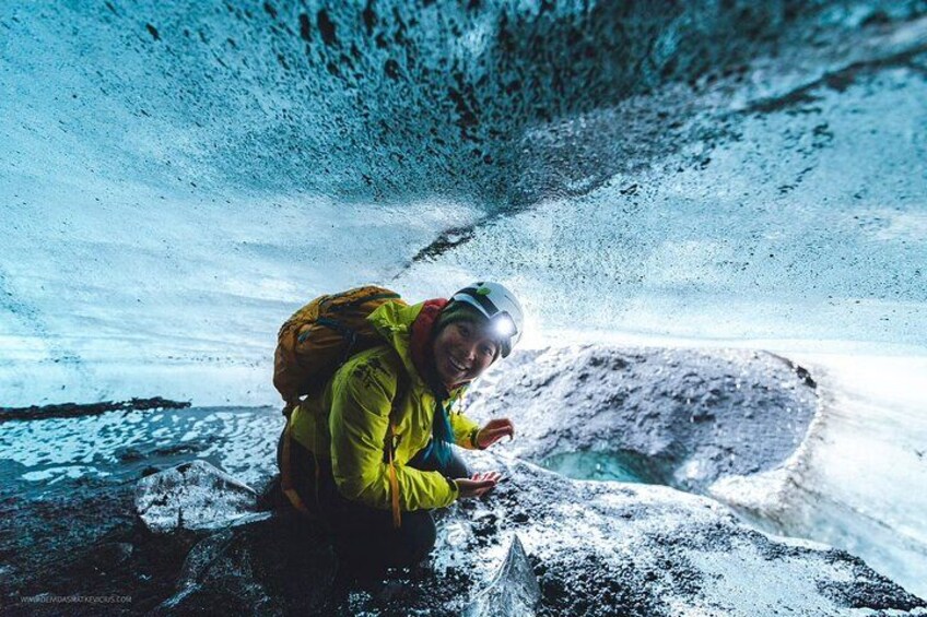 A person in a yellow jacket and helmet inside a cave with ice formations. 5