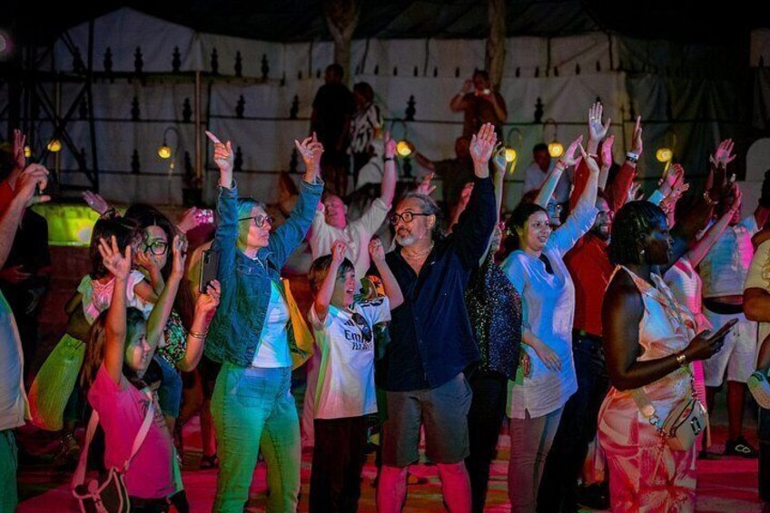 A group of people dancing with raised hands in a tented area. 5