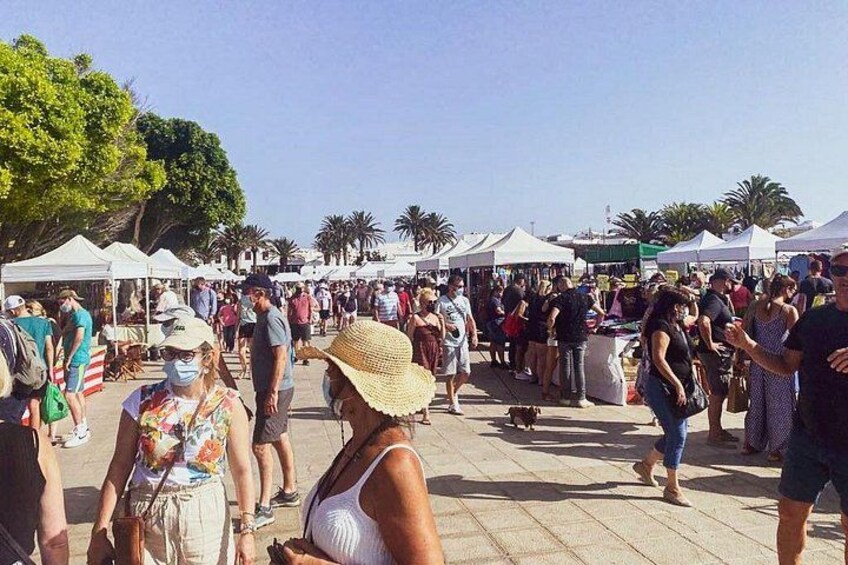 A crowded outdoor market with people walking and standing around. 3
