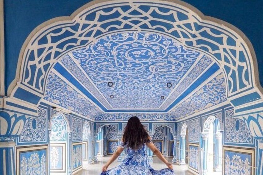 Une femme vêtue d’une robe bleue se tient dans une pièce dont le plafond et les murs sont décorés de motifs bleus et blancs. 4