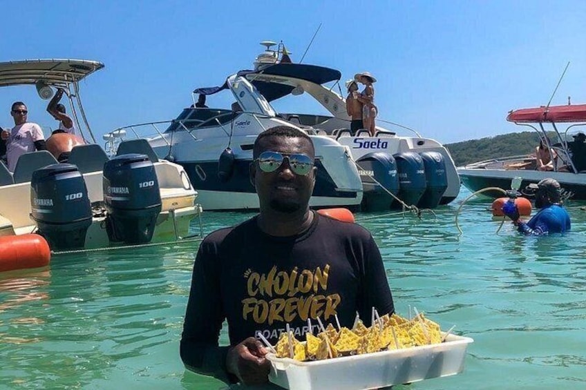 Una persona sostiene un recipiente con comida, con barcos al fondo y un cielo azul despejado. 2