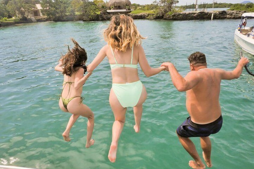 Tres personas saltando a un cuerpo de agua desde un bote. 1