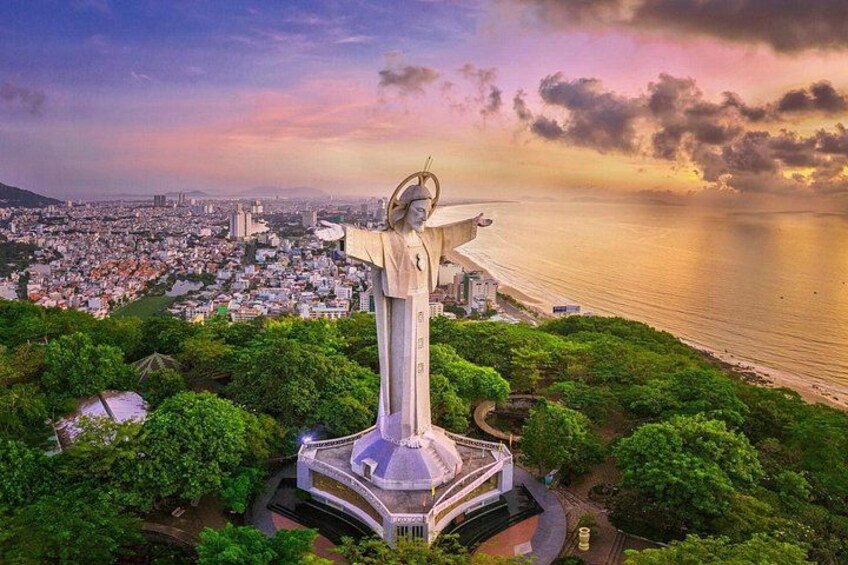 Eine große Statue auf einem Hügel mit Blick auf eine Stadt und den Ozean. 1