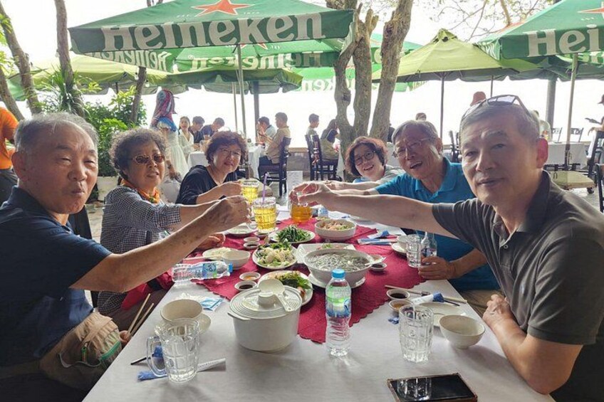 Eine Gruppe von Menschen speist im Freien an einem Tisch mit Sonnenschirmen mit Heineken-Branding. 3