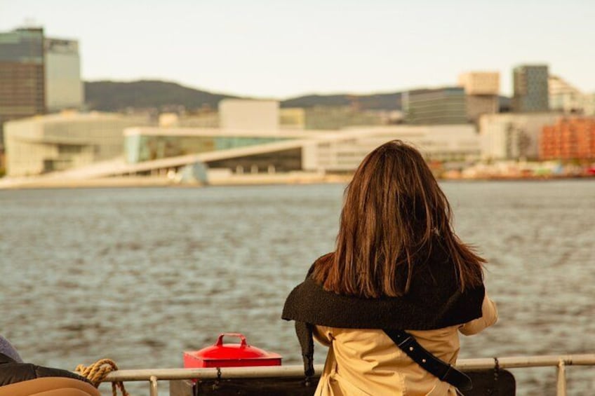 Two people sitting by a river with a cityscape in the background. 5