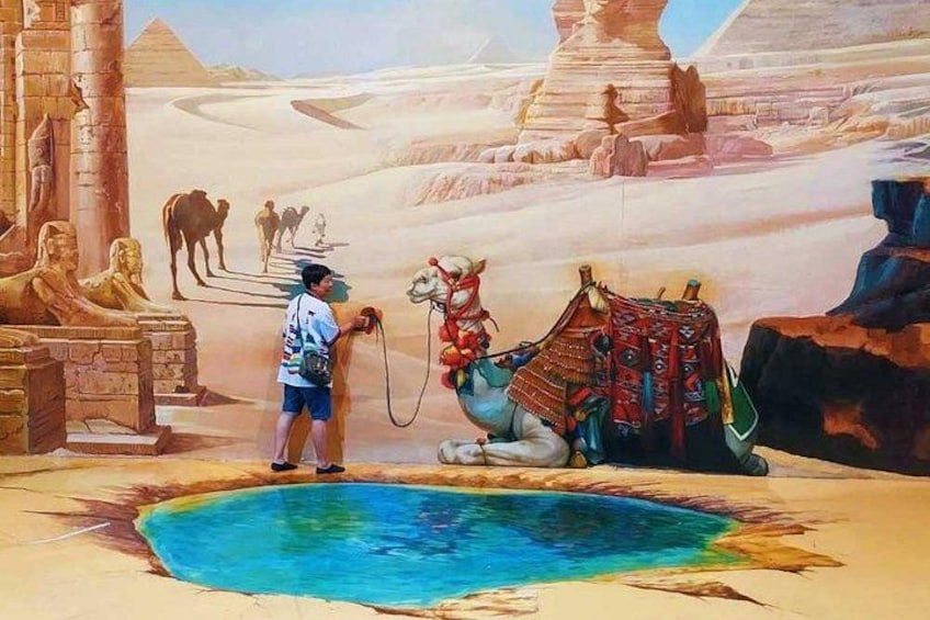 A desert scene with a camel, a person, and ancient Egyptian statues. 4