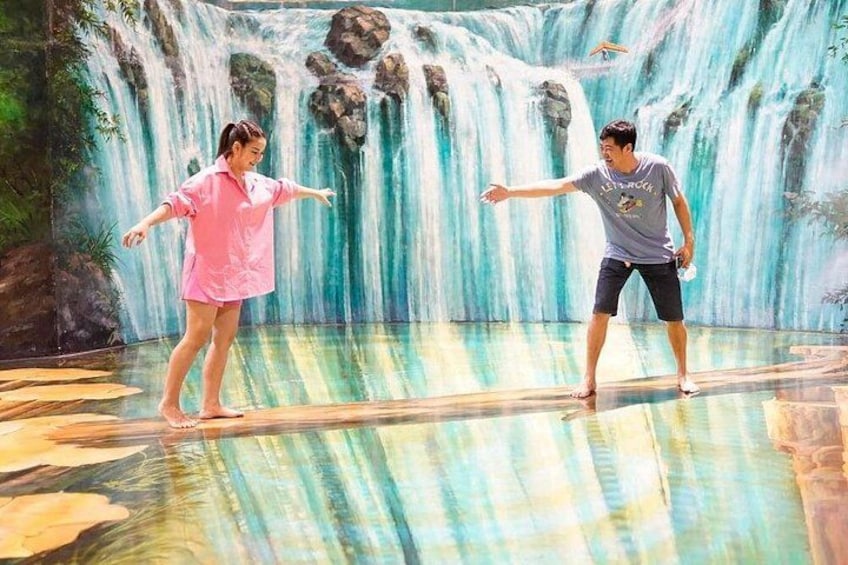 Two people standing on a platform with a waterfall backdrop. 2