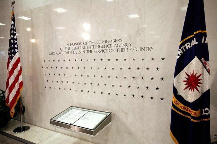 En minnesvägg med stjärnor och en plakett, en amerikansk flagga och en flagga från Central Intelligence Agency. 3