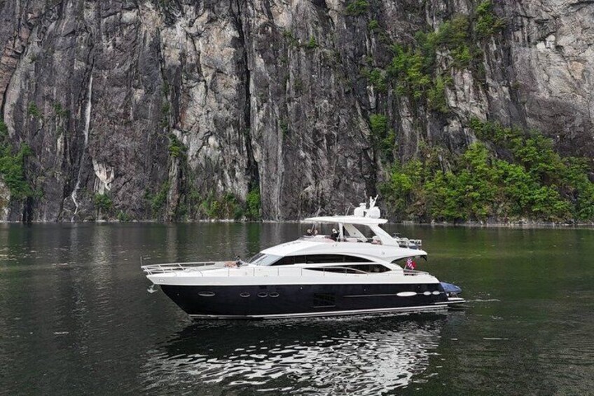 Uno yacht bianco su acque calme con una scogliera rocciosa sullo sfondo. 2