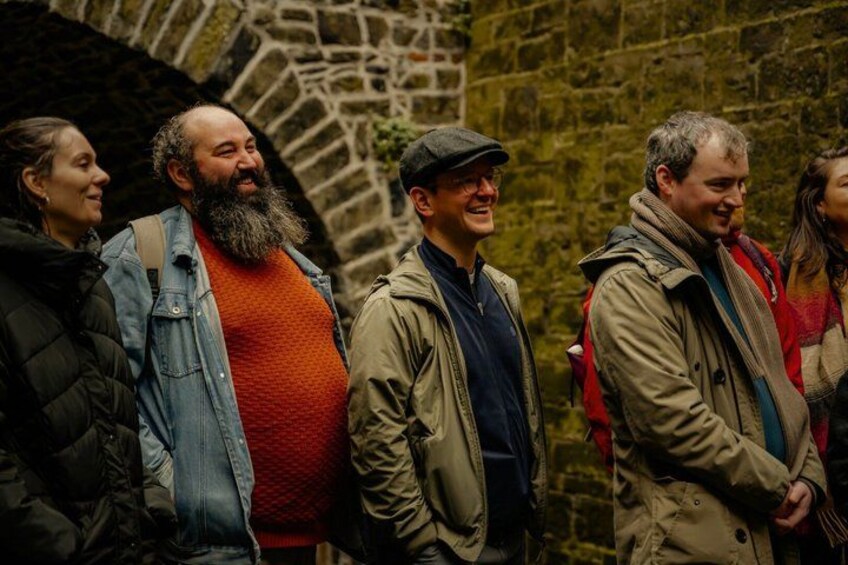 Un grupo de personas de pie frente a un muro de piedra. 5