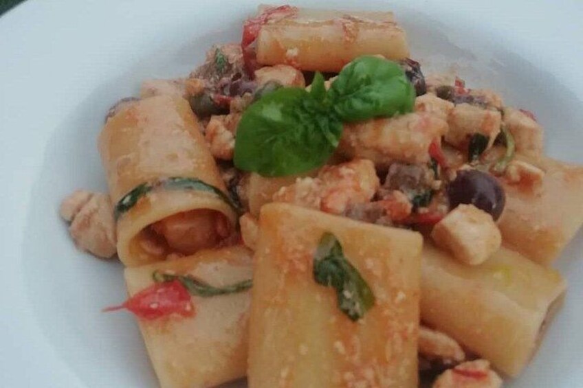 Un piatto di pasta con verdure e una foglia di basilico come guarnizione. 5