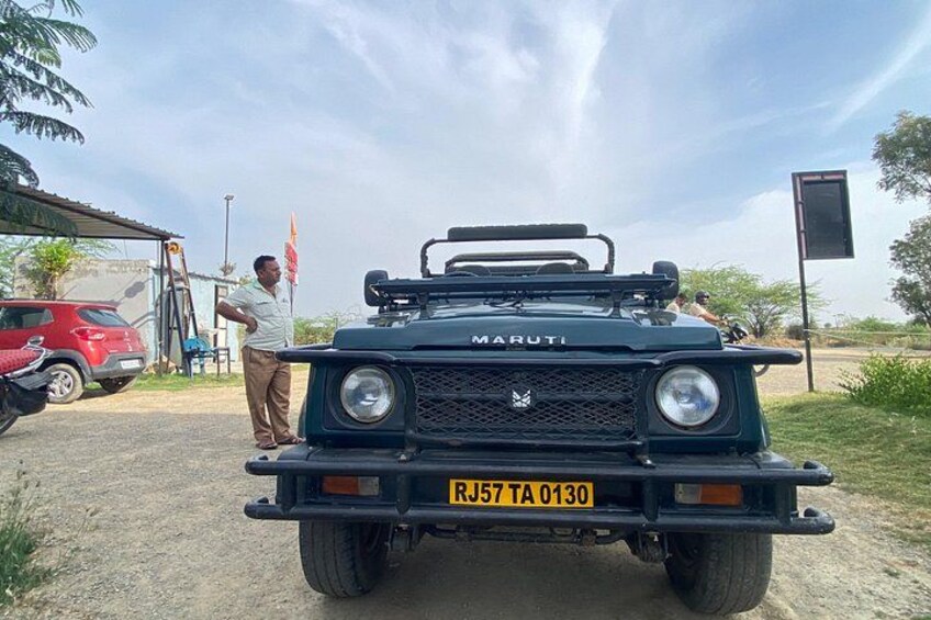 A black Maruti vehicle with a license plate RJ57TA0130 parked on a dirt road. 3