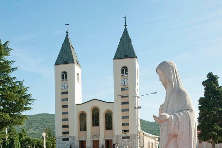 En kyrka med två torn och en staty av en person klädd i en lång mantel. 2