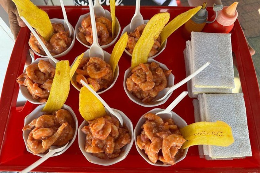 A tray with food items including shrimp and plantains. 1