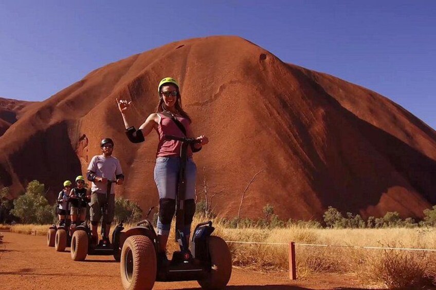 A person riding a Segway on a dirt path with a large red rock formation in the background. 5