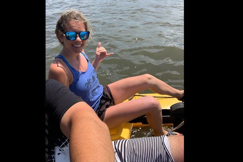 A person in a blue tank top and striped shorts on a yellow raft, with another person in a black shirt. 2
