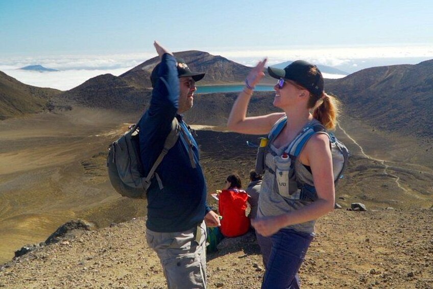Two hikers on a mountain trail with a lake and mountains in the background. 1
