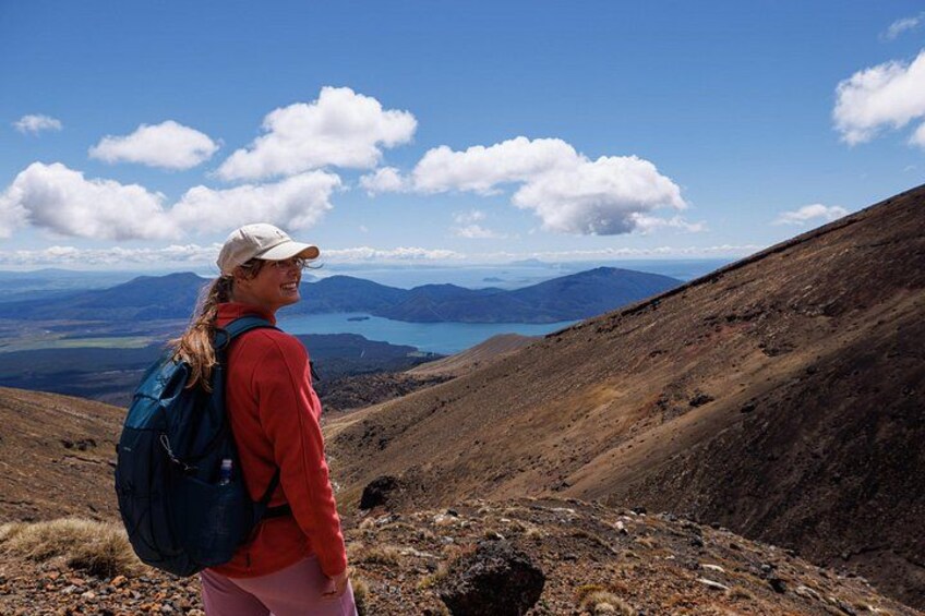 A person hiking on a mountain with a backpack, rocky terrain, and a lake in the distance. 2