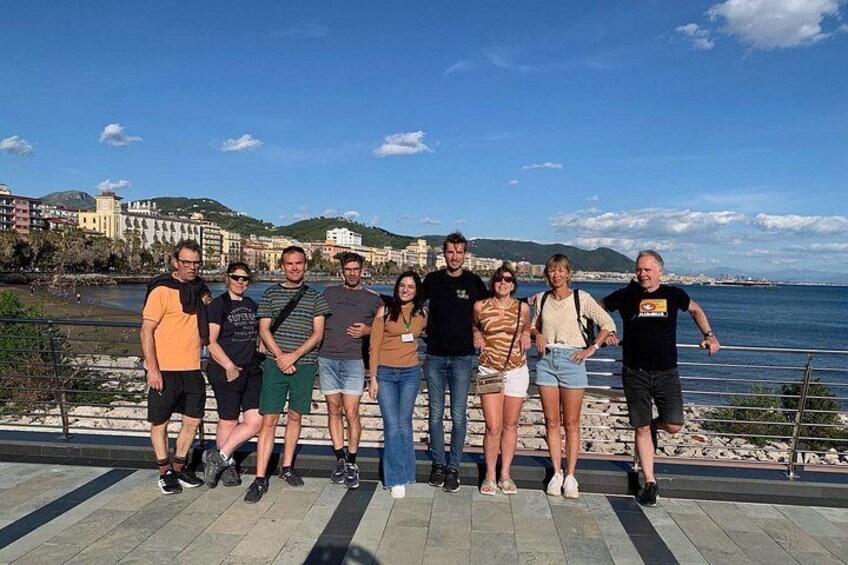 A group of people standing on a promenade with a coastal view. 1