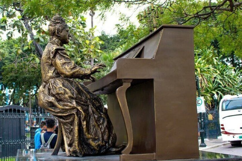 A bronze statue of a woman playing a piano. 1