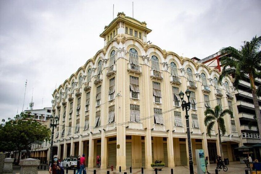 A large, ornate building with multiple balconies and columns, surrounded by palm trees and a few pedestrians. 5
