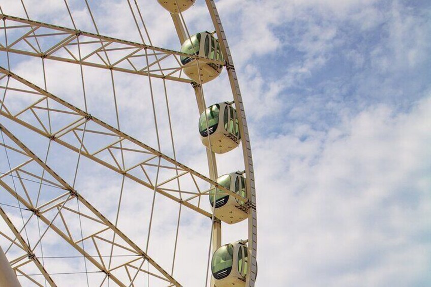 A Ferris wheel with multiple gondolas against a partly cloudy sky. 4