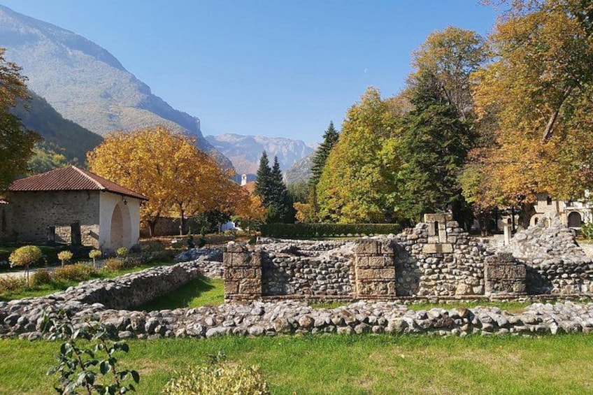 Des ruines antiques, un bâtiment en pierre et des arbres aux couleurs automnales dans une région montagneuse. 4
