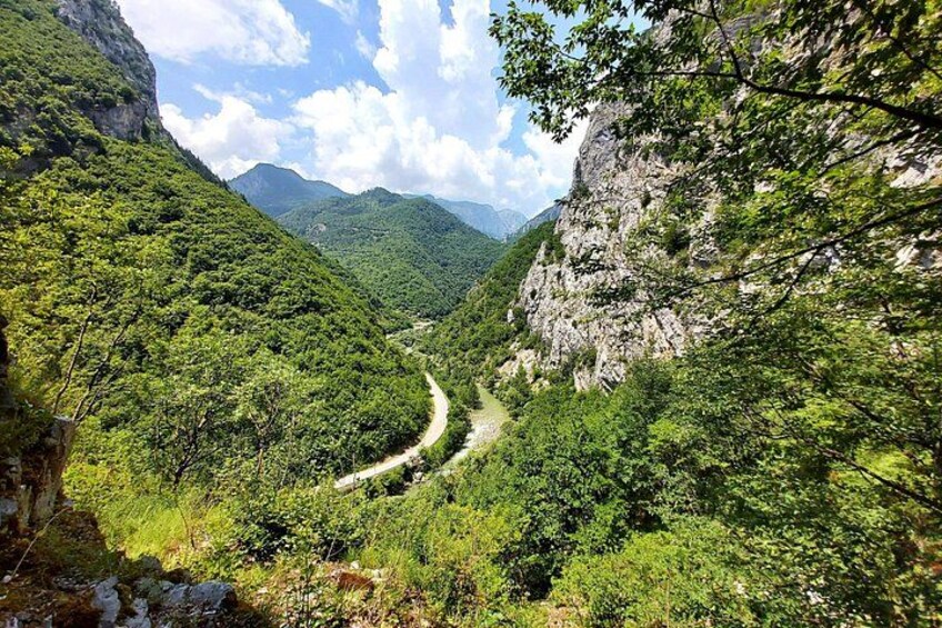 Une route de montagne sinueuse, bordée de forêts verdoyantes et de falaises rocheuses. 1