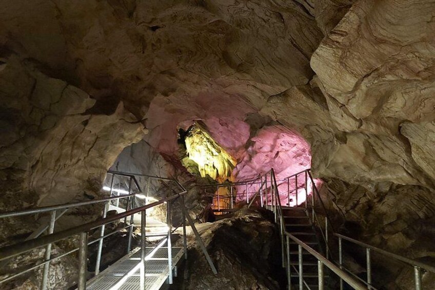 Une grotte avec un escalier menant à une chambre ornée de formations rocheuses roses. 5