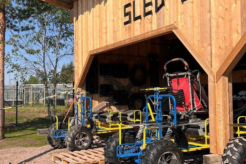 A wooden structure labeled 'SLED' with a sled and a blue and yellow sled trailer outside. 4