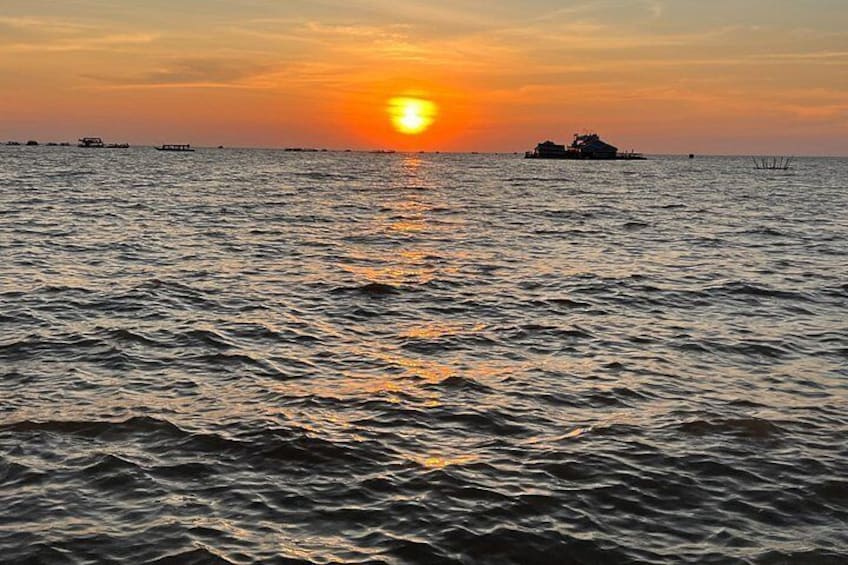 A sunset over a body of water with boats and a ship in the distance. 3