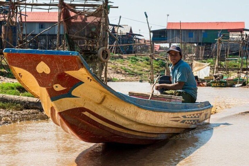 A man in a boat with a colorful design, on a waterway with buildings in the background. 2