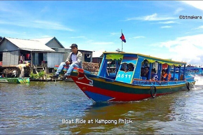 A colorful boat with a man sitting at the front, surrounded by water and wooden structures. 4