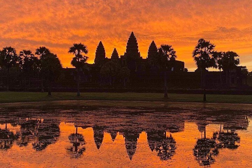 A sunset with a reflection of a temple and trees in a body of water. 2