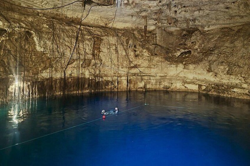 A cave with a blue pool and a rope. 4