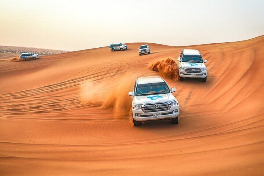 Vier Autos fahren auf einer Sanddüne. 1