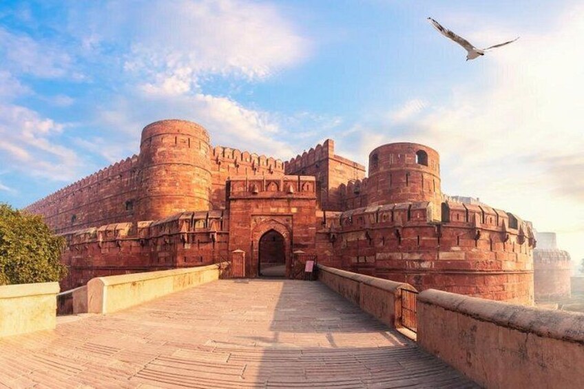 A historic fort with large red walls, a central gateway, and a paved walkway. 4