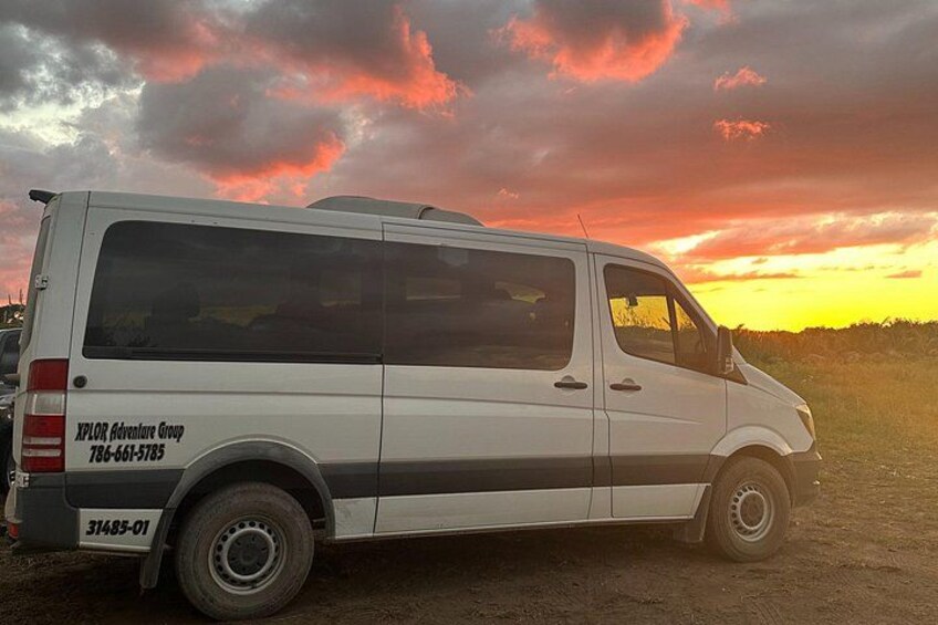 Una camioneta blanca estacionada en un camino de tierra con un atardecer al fondo. 4