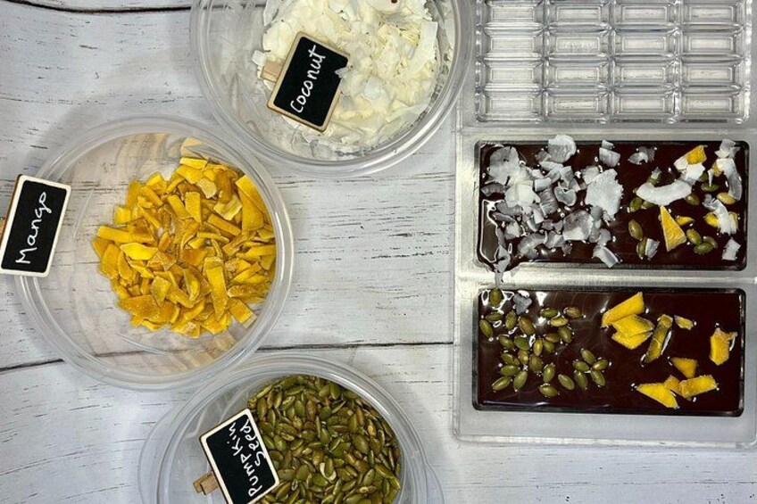 Vier Behälter mit getrockneten Früchten und Samen, beschriftet mit 'Kokos', 'Mango' und 'Sesam'. 5