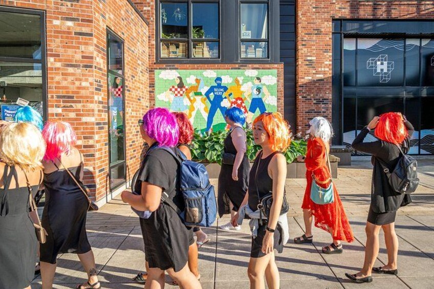 Un groupe de personnes se tient devant un bâtiment orné d’une fresque murale aux couleurs vives. 4