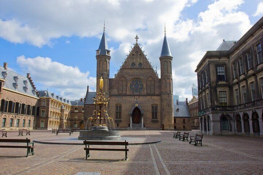 A historic church with twin towers and a central clock, surrounded by a cobblestone square with benches. 4