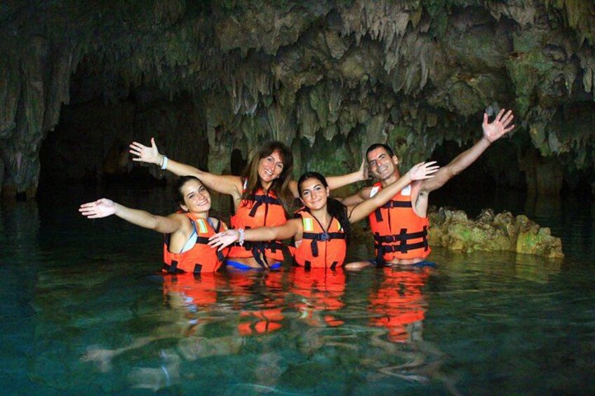 Un groupe de personnes se trouve dans une grotte où il y a de l’eau, et elles portent toutes des gilets de sauvetage. 3