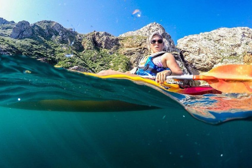Une personne pratiquant le kayak sur une rivière, avec des montagnes rocheuses en arrière-plan. 1