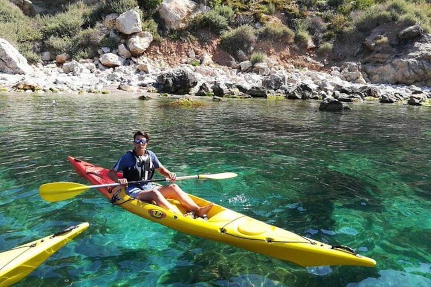 A person kayaking on a clear river surrounded by rocks and vegetation. 5