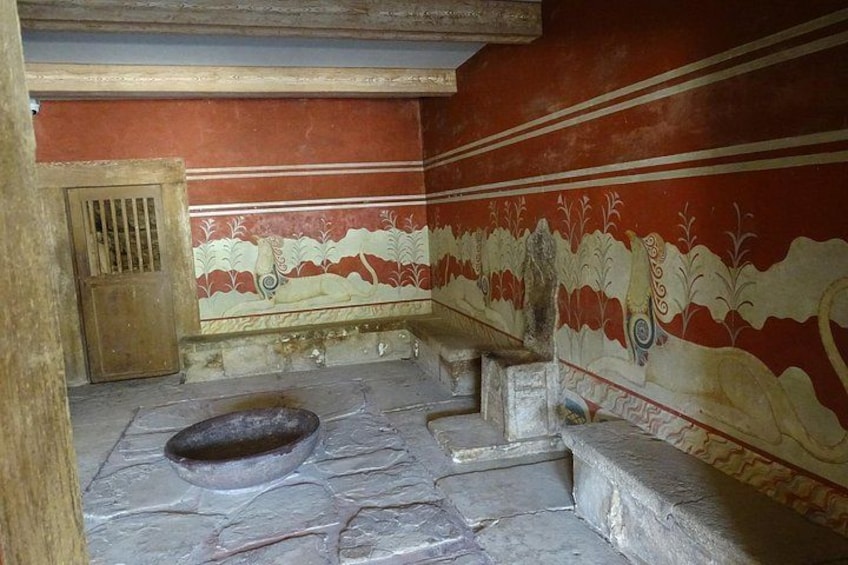 A stone room with a large basin, steps, and decorative wall paintings. 4