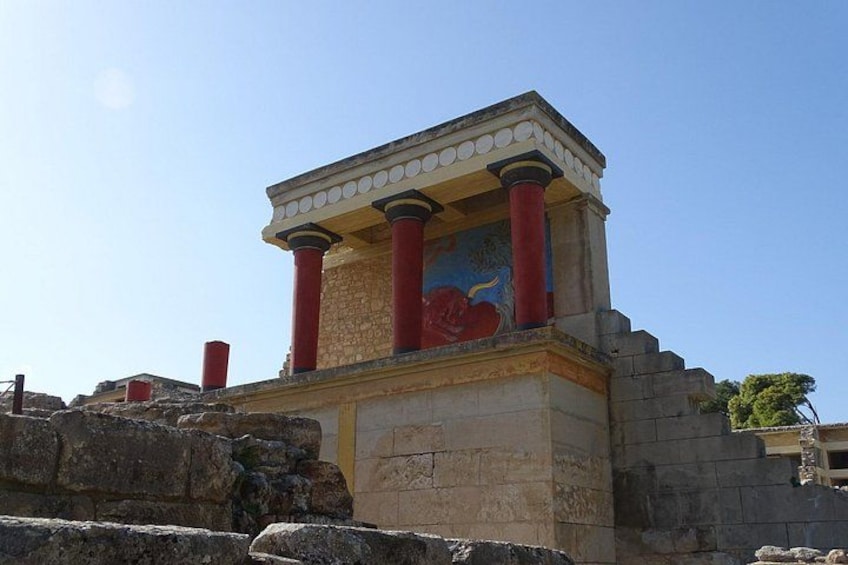 An ancient structure with red columns and a painted frieze. 1