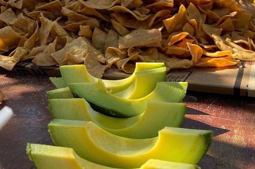 Sliced avocado, tortilla chips, and a cutting board. 2